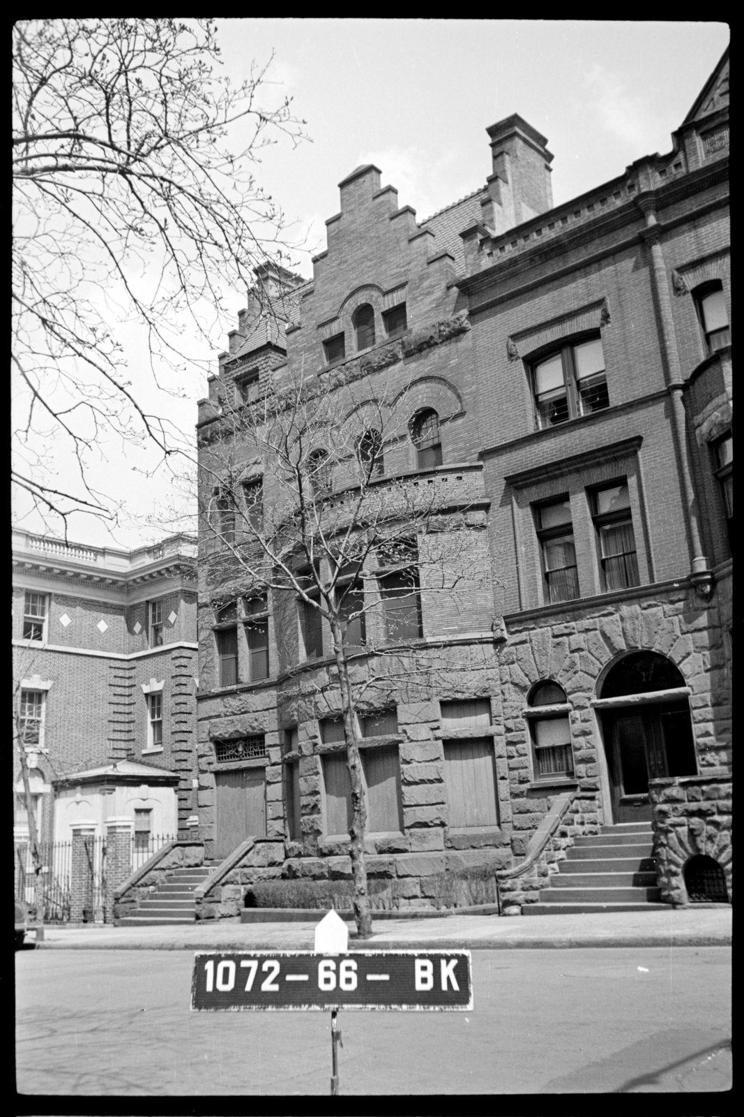 Archival black and white photograph of the building from the street, with a stepped gable, arched windows and a stone stoop