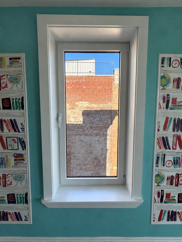 New white framed window in a teal room, with narrow decorative panels on both sides