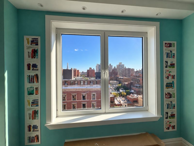 Wide new white framed window in a teal room with tall narrow panels on both sides, looking out over the skyline