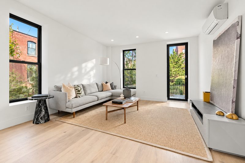 Living room with a tall black framed window, a black framed glass door and a gray sofa