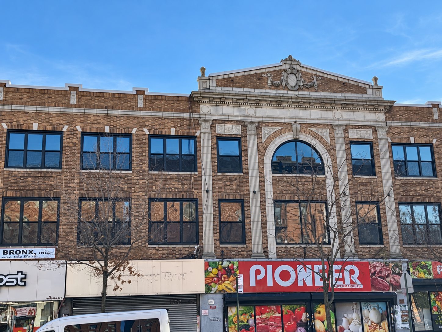 The former Willis Theatre building at 250 Willis Avenue, with its decorative pediment, arched center window and rows of new dark framed windows above the storefronts