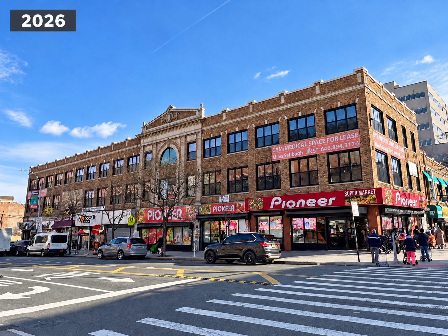 The same corner view after the window replacement, with new dark framed windows across the brick upper floors