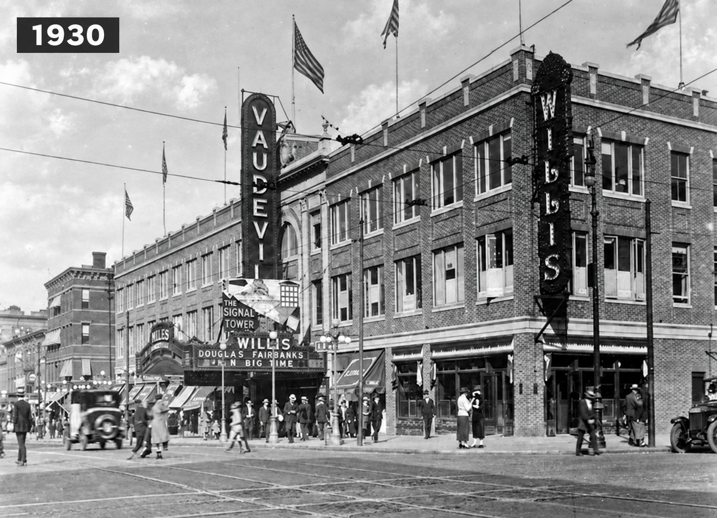 Restored archival view of the Willis Theatre corner, labeled 1930, with the theatre marquee, tall vertical signs, pedestrians and early cars