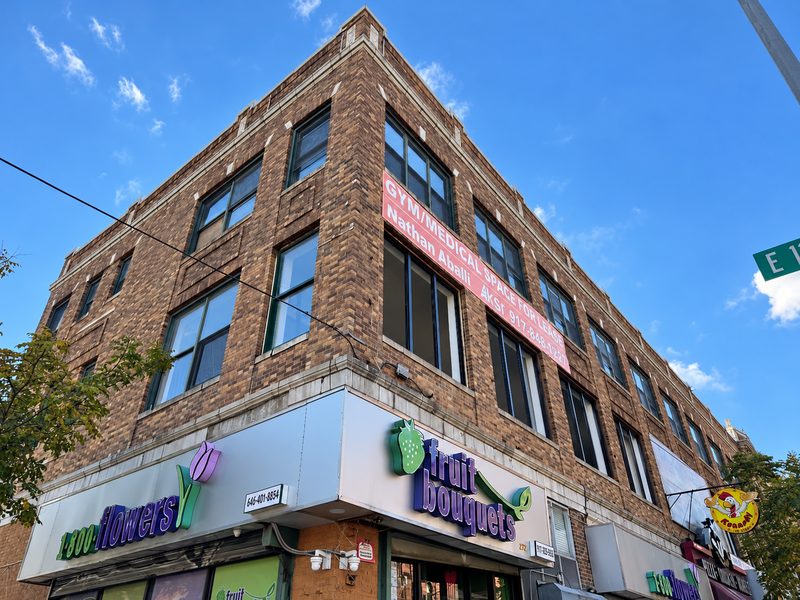 Low angle view of the building corner with new windows on the brick upper floors above a flower shop