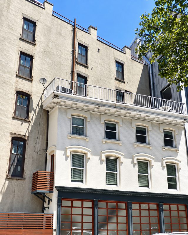 White painted lower stories with ornamental window heads beneath a rooftop railing, with the tan upper floors and their new windows above